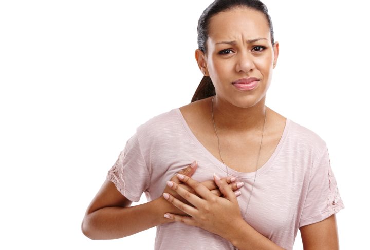 Woman, breast and cancer holding chest in discomfort, pain or ache against a white studio background. Portrait of isolated young female clutching boobs touching painful area, sore or inflammation.